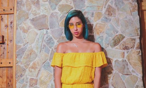 Portrait of young woman standing against wall