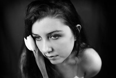 Close-up portrait of young woman against black background