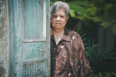 Portrait of young man standing against closed door