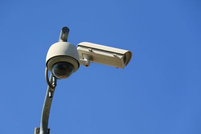 Low angle view of telephone pole against clear blue sky