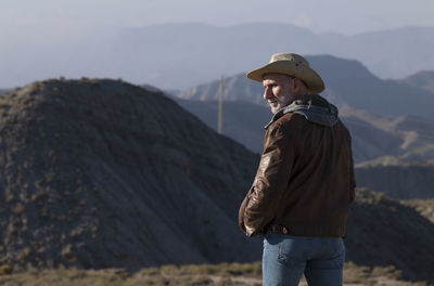 Adult man in cowboy hat looking at view of tabernas desert, almeria, spain