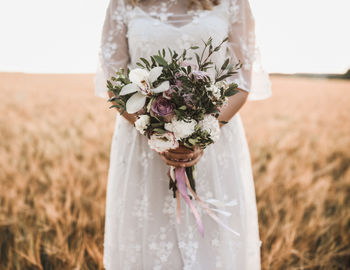 Midsection of bride holding bouquet