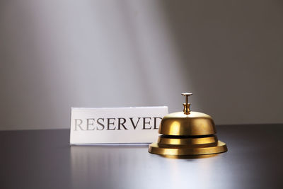 Close-up of reserved place card with service bell on table