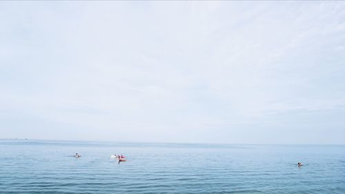 People swimming in sea against sky