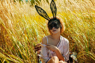 Fashion model in rabbit mask posing in field.