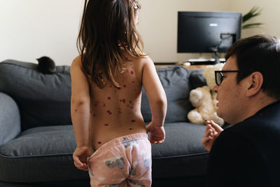 Rear view of girl with spots on back at home