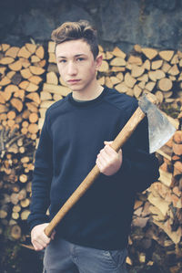 Portrait of teenage boy cutting log