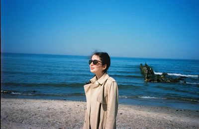 Young woman on beach against clear sky