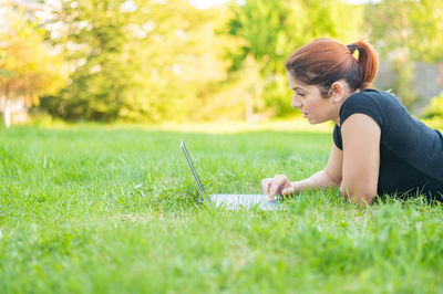 Side view of woman sitting on grass field