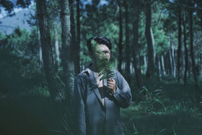 Man with fern leaf in forest