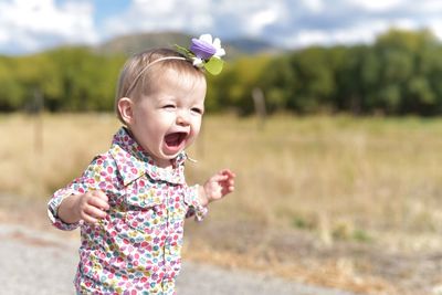 Cute girl shouting while standing on road during sunny day