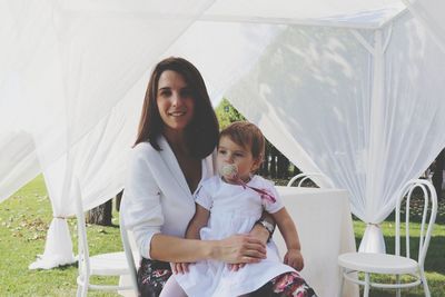 Portrait of smiling mother holding daughter while sitting in park