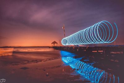 Pier at beach against sky during sunset