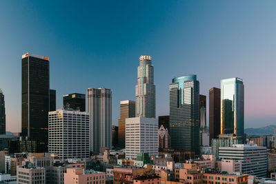 Modern buildings in city against clear blue sky