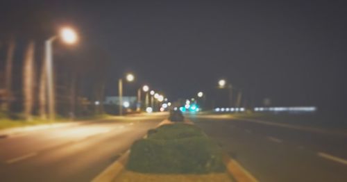 Illuminated road against sky at night