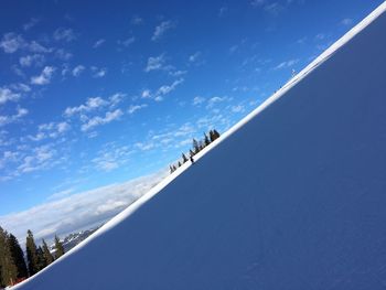 Low angle view of people on snowcapped mountain against sky