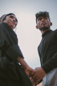 Low angle view of couple standing against sky