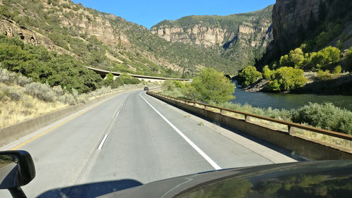 Road amidst mountains seen through car windshield