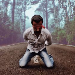 Young man sitting on tree trunk