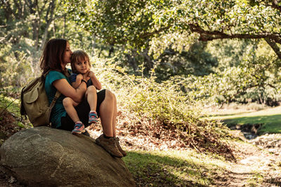 Woman with daughter sitting in forest