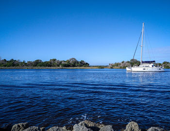 Sailboats sailing in sea against clear blue sky