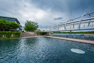 Bridge over river by city against sky