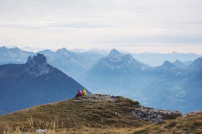 People sitting on mountain against sky