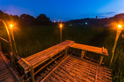 Empty wooden bench on boardwalk at night