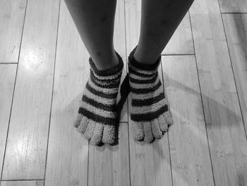 Low section of woman wearing socks while standing on hardwood floor