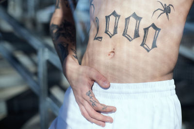 Midsection of shirtless man with tattoo