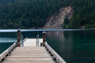 Pier over lake against trees and mountains