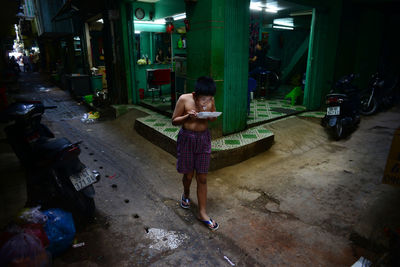 Woman standing on street against illuminated buildings at night