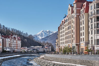 Road by buildings against clear sky during winter