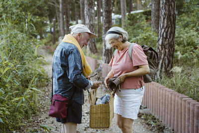 Happy senior couple holding wicker basket while hiking in forest