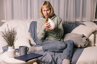 Young woman using phone while sitting on sofa at home