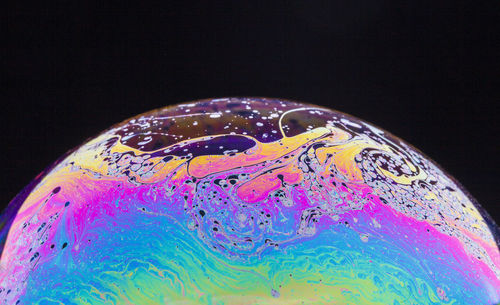 Close-up of bubbles over water against black background