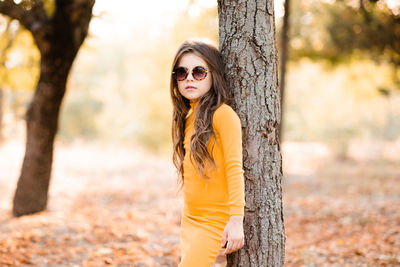 Cute stylish child girl 4-5 year old wear yellow knitted dress and sun glasses posing outdoor