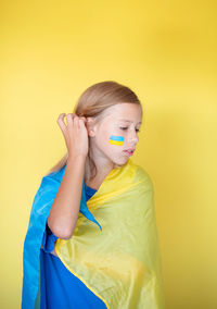 Close-up portrait of young woman against yellow background