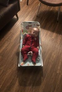 High angle view of boy sitting on wooden floor at home