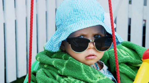 A one-year-old girl in a panama and sunglasses, like an important lady, sits in the children's