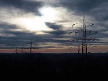 Low angle view of silhouette electricity pylon against sky during sunset