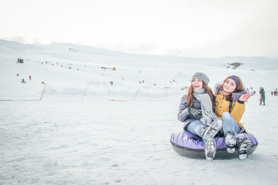 Full length of women sitting on snow during winter