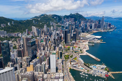 Aerial view of city by sea and buildings against sky