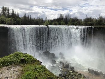 Scenic view of waterfall against sky