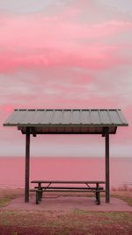 Wooden bench against sky at sunset