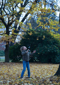 Boy playing with autumn leaves at park