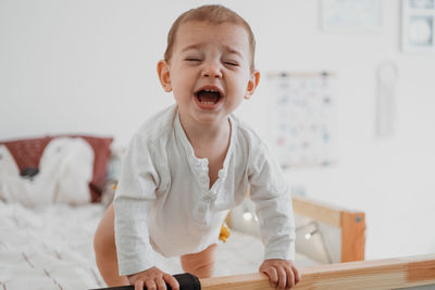 Close-up of crying baby on bed