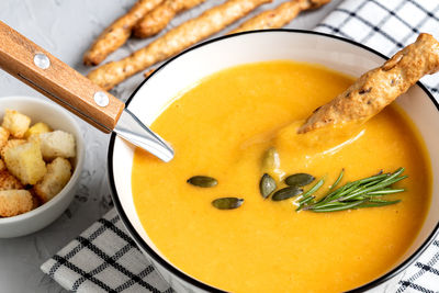 Pumpkin and carrot soup with cream, pumpkin seeds, croutons and grossini bread 