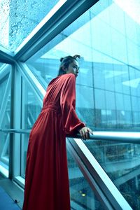 Low angle view of woman standing against glass window