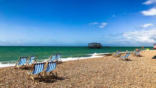 Chairs on beach against blue sky